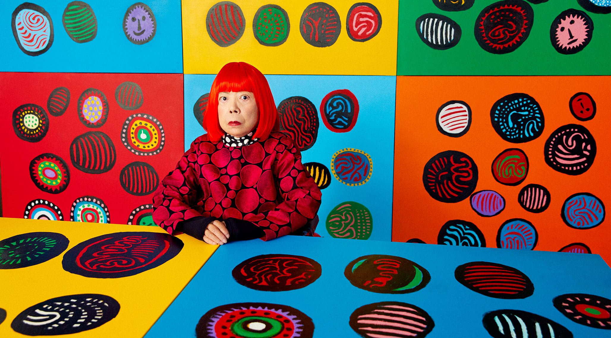 A photo of Yayoi kusama with her paintings. Photo by  Yusuke Miyazaki.