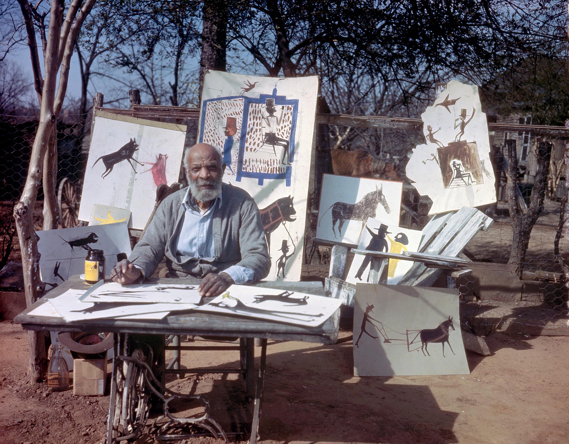An archival photo of Bill Traylor working under a shade tree in a Montgomery neighborhood