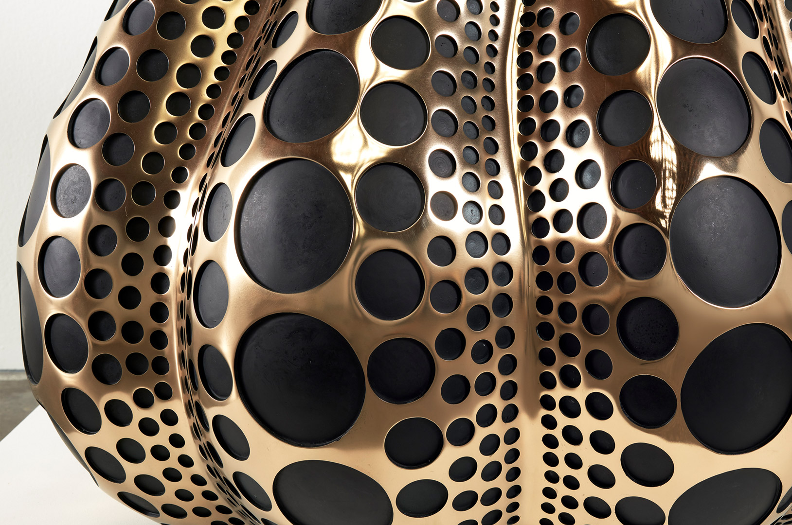 A detail view of a mirror polished bronze, dye, and acrylic lacquer sculpture by Yayoi Kusama, titled Pumpkin (M), dated 2016.